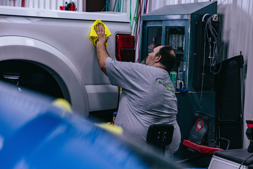 A Detail Depot employee puts the finishing detailing touch on a white truck in the car detailing shop.